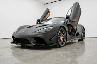 Koenigsegg Agera R en carbone noir mat exposée dans un showroom blanc épuré avec reflets au sol