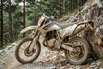 Moteur d'enduro encrassé de boue sur un sentier rocheux en forêt, illustrant les risques de surchauffe et de casse moteur en terrain difficile